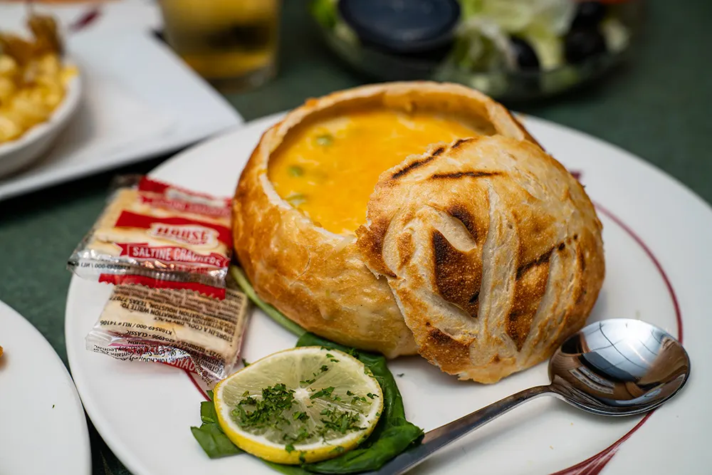 A bread bowl of soup with lime and a spoon