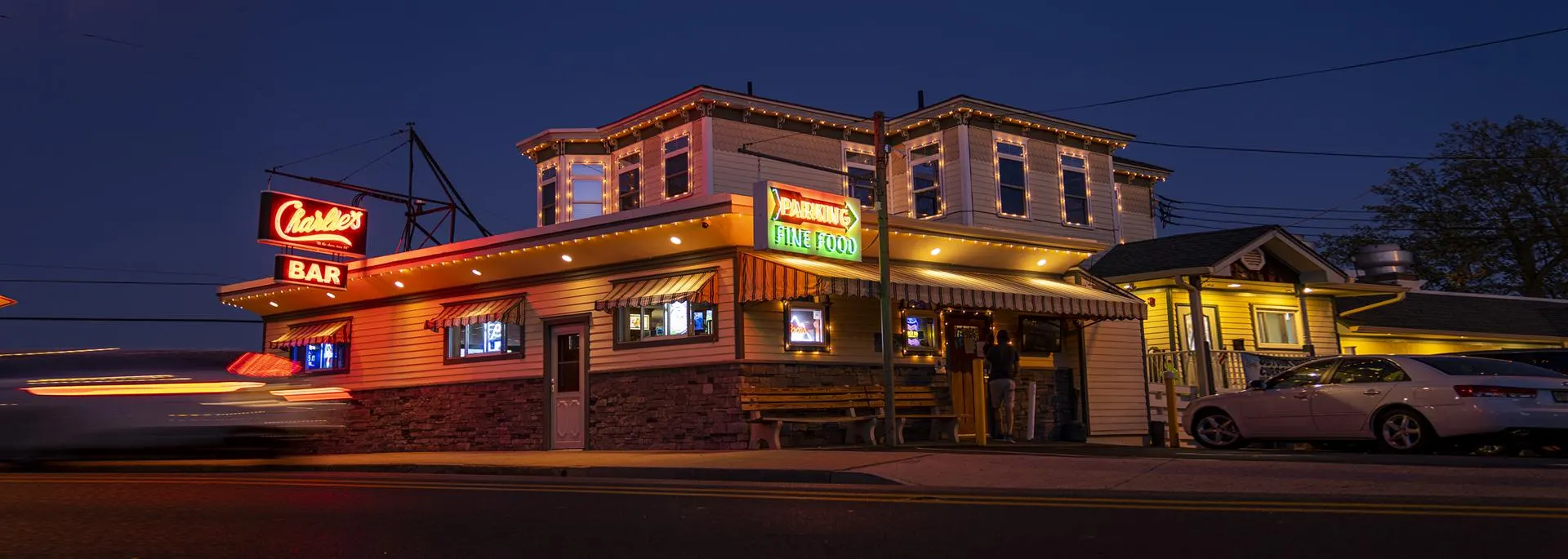 Charlie's Bar at night, lit by neon and string lights on Shore Road