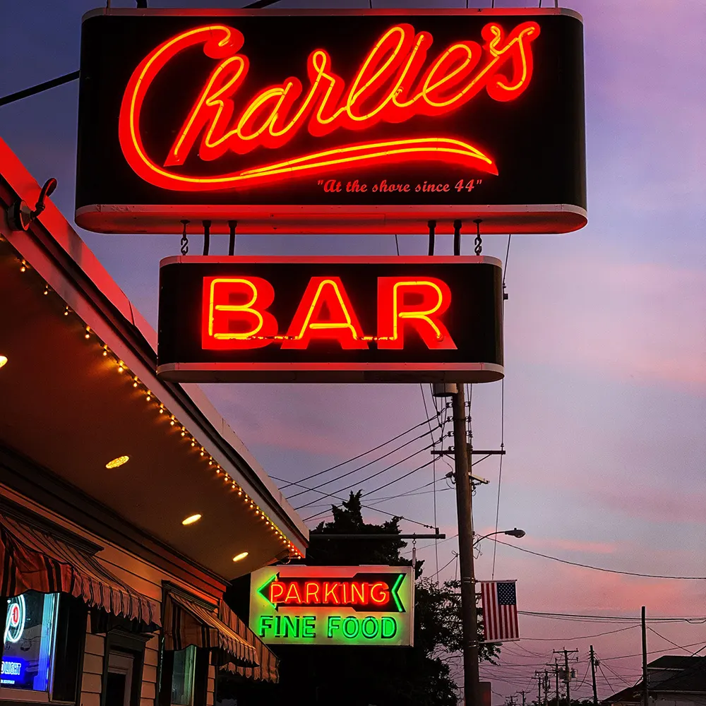The neon Charlie's and BAR signs at dusk